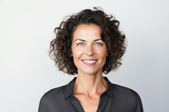 femme brune de 50 ans cheveux court fris&eacute;s souriante sur fond blanc