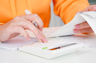 Inflation. Woman uses calculator to calculate expenses for shopping. Receipts and household expenses