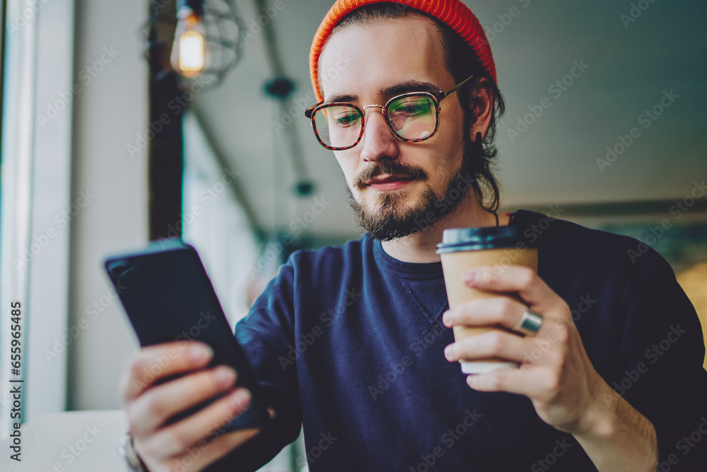 Poster handsome blogger checking notification for smartphone application during coffee time
