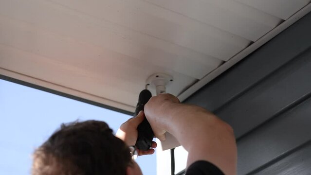 man installs a video camera on his home for protection and security