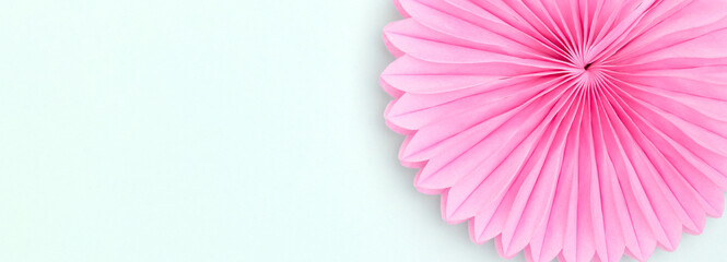 Banner with pink tissue paper fan on a blue background. Festive concept with copy space.