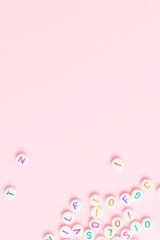 Beads with letters on a pink background. Place for your design.