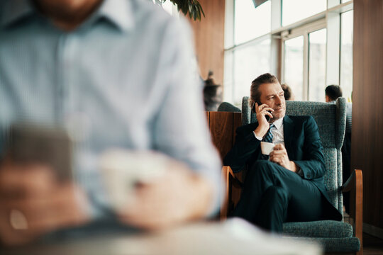 Mature businessman talking on a phone in a cafe