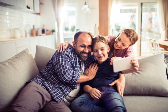 Happy young caucasian family having a selfie on the couch at home