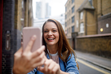 Happy young caucasian woman having a video call on her phone in the city