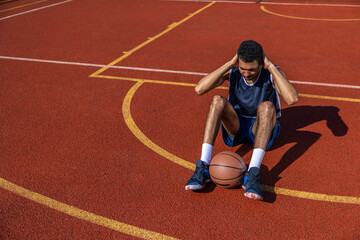 Black man doing sit ups and crunches exercising abdominal muscles outdoor on basketball court.