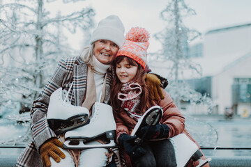 Grandmother with granddaughter in winter at outdoor ice skating rink.