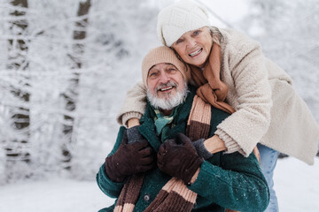 Close-up of elegant senior man with his wife in the snowy park.