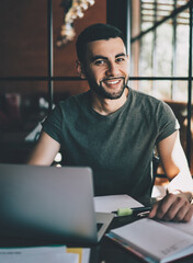 Smiling man with laptop sitting at table