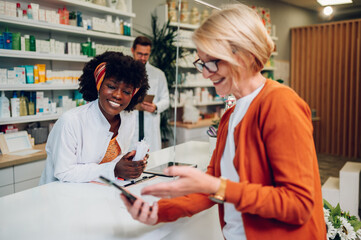 Obraz premium African american woman pharmacist selling drugs to a senior customer in a pharmacy