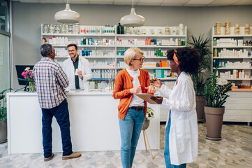 African american woman pharmacist talking to a senior customer in a pharmacy