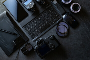 Equipo fotográfico profesional. Estación de trabajo de fotografía digital sobre fondo negro. Vista superior de cámara digital, flash, lente y computadora portátil.