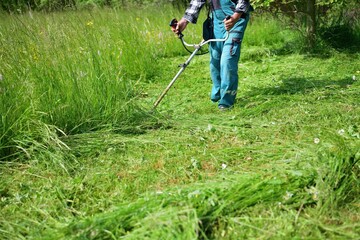 The gardener mows the grass in a modern way with a petrol mower