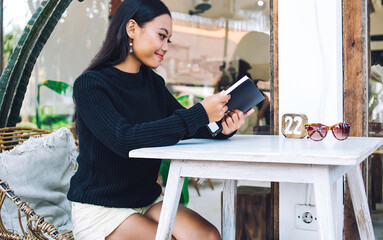 Young Asian female with notebook at cafe table