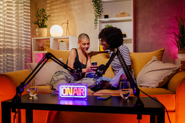 Couple of multiracial women recording internet podcast while using mobile phone