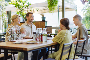 Big family with children and a small baby at family dinner in a restaurant.