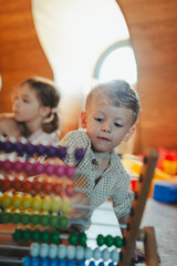 Little boy playing in the children's room with a wooden abacus.