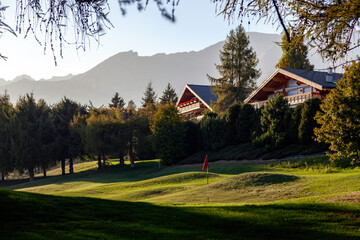 terrain de golf avec des chalets dans la station de montagne suisse de Crans Montana au coucher du...