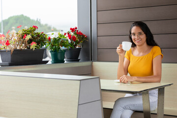 Cheerful woman drinking coffee in cafe