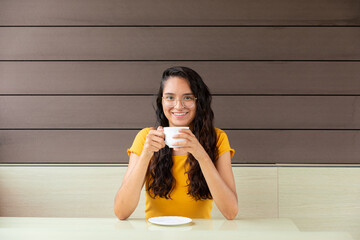 Cheerful woman drinking coffee in cafe
