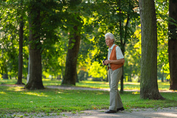 Fototapeta premium Senior man spending free time outdoors in nature, watching forest animals through binoculars.