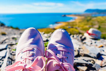 Naklejka premium Female legs in sneakers against coast landscape, Spain.