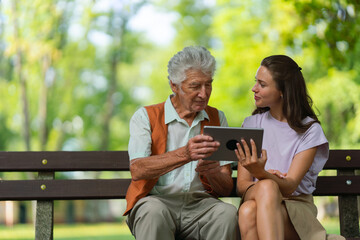 Caregiver helping senior man to shop online on tablet.