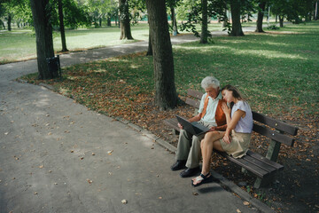 A widower is sitting on a bench in the park with his granddaughter, mourning his deceased wife.