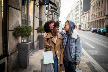 Young mixed lesbian couple embracing each other while shopping and walking in the city