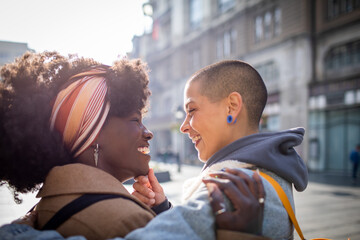 Young mixed lesbian couple embracing each other while shopping and walking in the city
