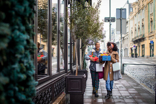 Young mixed lesbian couple buying Christmas presents while walking in the city - Powered by Adobe