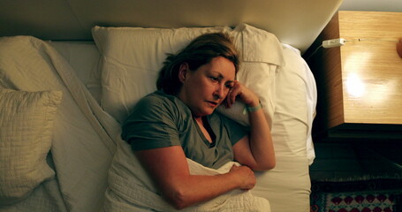 Thoughtful older woman switching lamp light OFF, person going to sleep