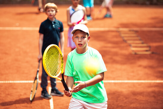 Young boy setting up for a forehand on a clay court