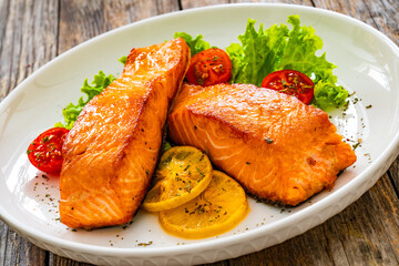 Seared salmon steaks with lettuce and lemons on wooden table
