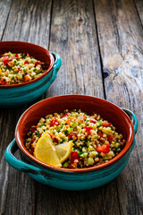 Tabbouleh salad -  bulgur groats, tomatoes, cucumber, parsley, lemon, onion and fresh mint leaves on wooden background
