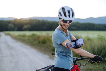 Diabetic cyclist connecting continuous glucose monitor with her smartphone to monitor her blood...