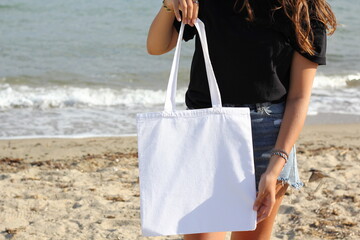 Blank white tote bag canvas fabric with handle mock up design. Close up of woman holding summer eco...