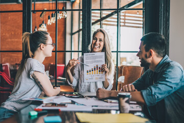 Smiling woman showing chart to colleagues