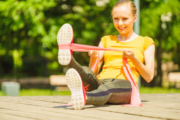 Girl doing exercise outdoor, using resistance fit band.