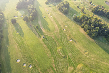 Aerial view of a big golf course during sunset, warm sunlight, green mowed grass