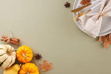  Preparing a Thanksgiving table for a memorable celebration. Top view shot of plates, cutlery, napkin, pumpkins, classic fall elements on pastel green background with advert zone © Goncharuk film