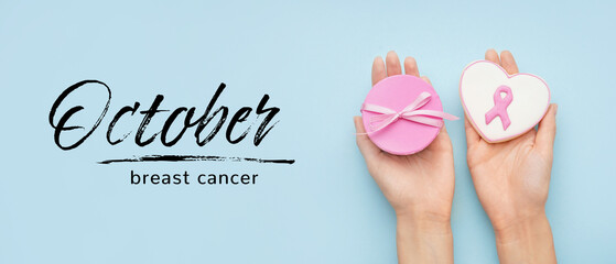 Female hands holding cookies on light blue background. Banner for Breast Cancer Awareness Month