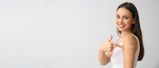 Young woman with medical patch on arm against light background with space for text. Vaccination...