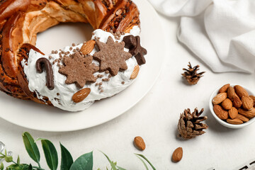 Obraz na płótnie Canvas Plate with tasty Christmas pastry wreath, almond and cones on light background, closeup