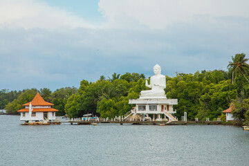 white Buddha figure sits over lake.