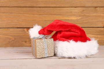 Obraz na płótnie Canvas Santa hat with gift box on grey wooden table