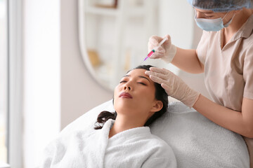 Young Asian woman receiving injection in beauty salon. Skin care concept