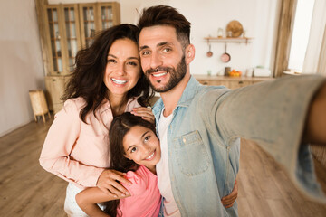 Fototapeta premium Family selfie. Happy father, mother and their daughter taking photo, parents and child girl posing and smiling at camera