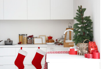 Small fir tree, gift box and Christmas decor on white kitchen counter