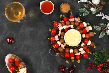 Christmas and New Year's dishes, a set of snacks and refreshing drinks for the holiday table. A plate with canapes of tomatoes, mozzarella cheese, olives, black olives and grapes on a dark table
